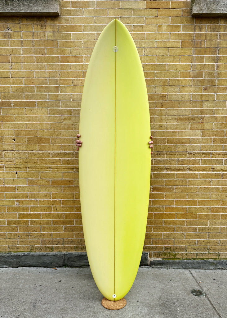 A Simon Shapes 6'4" Kegg performance short board with a yellow resin fade.