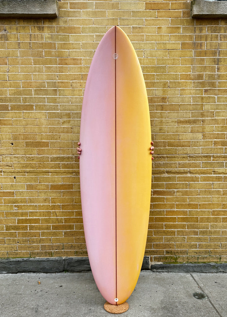 A Simon Shapes 6'3" Kegg performance short board with a pink and orange resin fade.